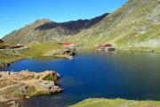 An ice-cold pond in the mountains with a nearby summer resort. - A mountain lake